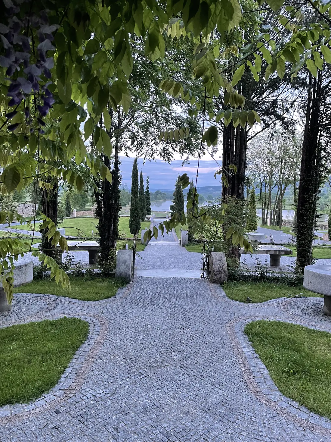 Une allée pavée sous la glycine, ouverte sur l'étang
